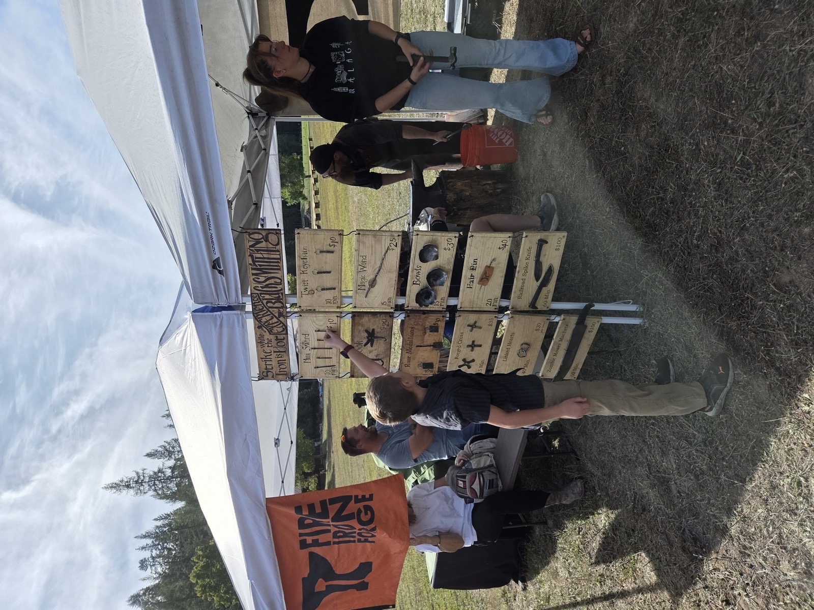 A vendor booth under a tent with a rack of branded wooden boards