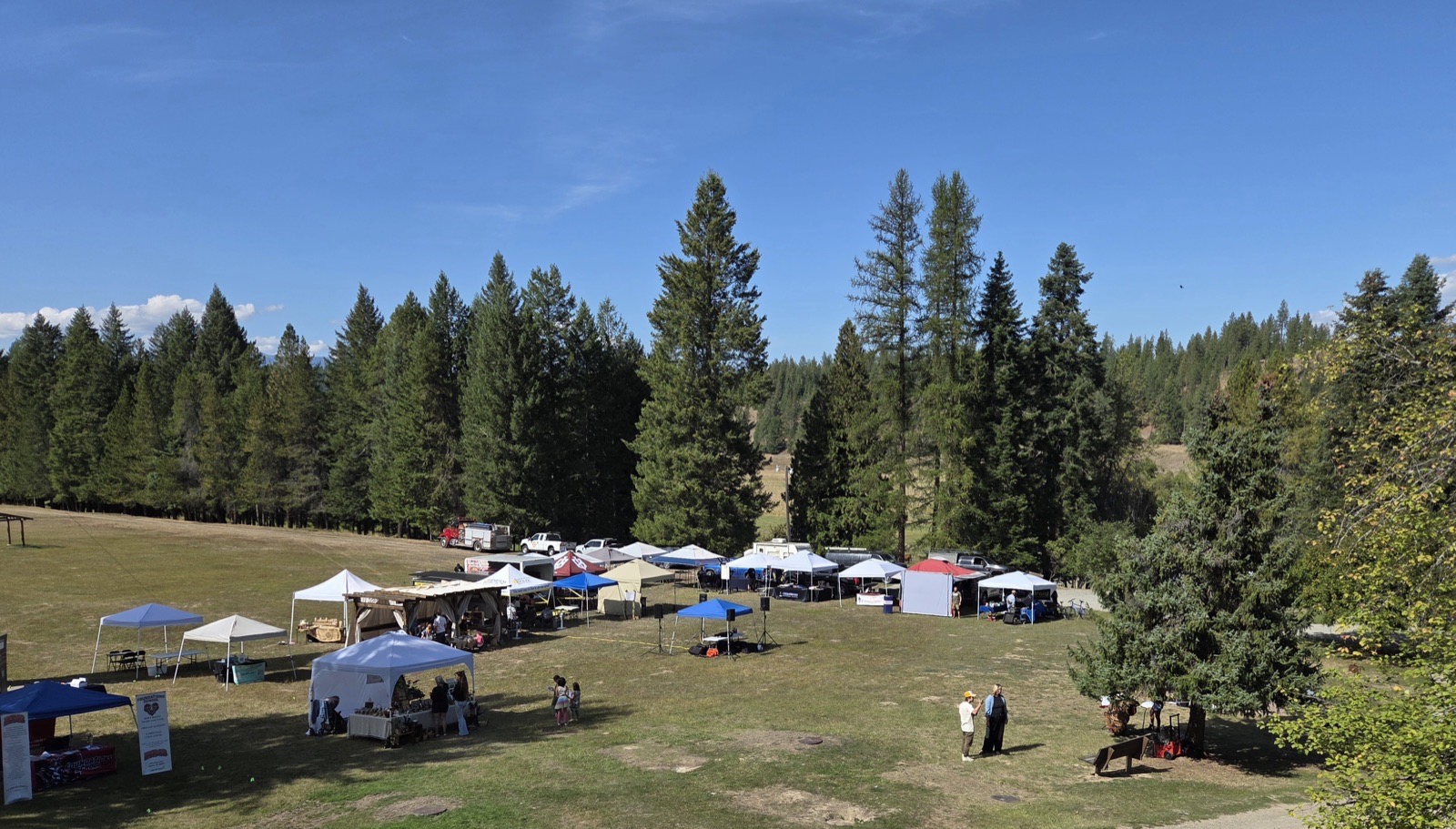 The vendor tents on the field at Shiloh Echo, seen from above, pines behind