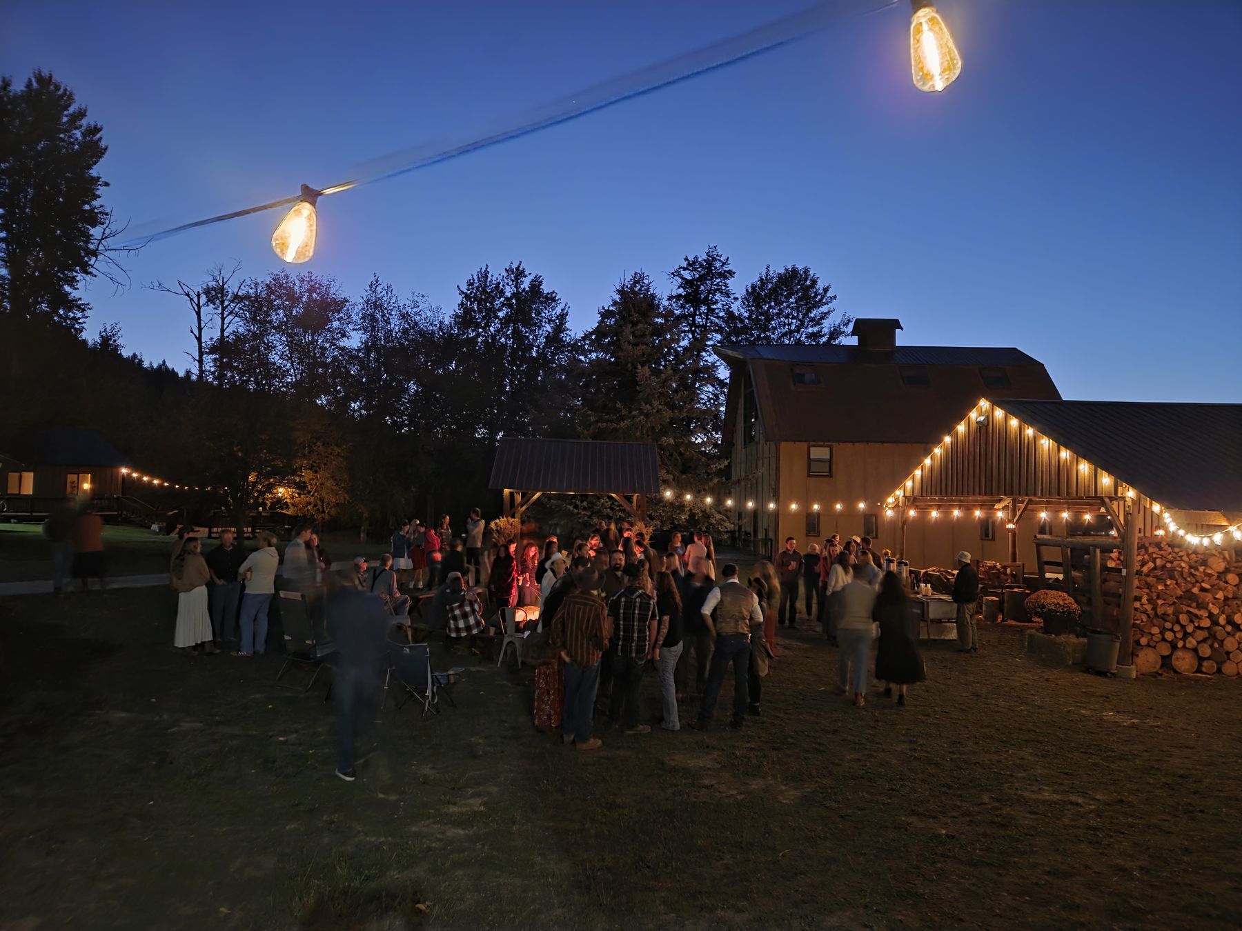 People gathered outside under string lights at dusk