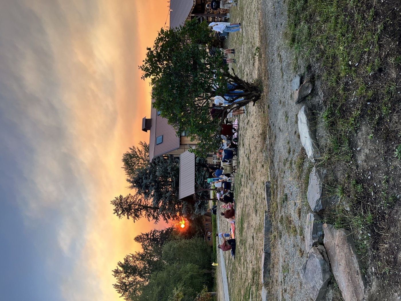 Sunset over the lawn, the crew gathered on blankets and chairs as the sun drops behind the trees